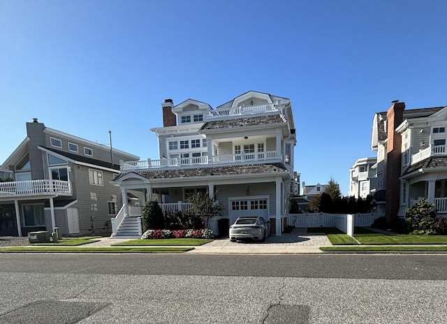 view of front of house with covered porch, a balcony, a garage, and central AC unit