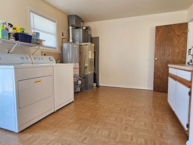 clothes washing area with baseboards, water heater, washer and dryer, cabinet space, and heating unit