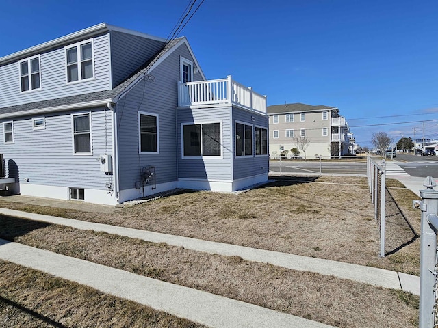 view of property exterior with a balcony, fence, and roof with shingles