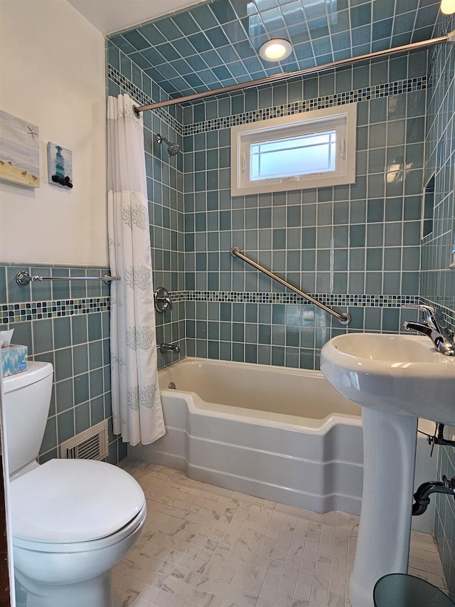 bathroom with visible vents, toilet, tile patterned flooring, shower / bath combination with curtain, and tile walls