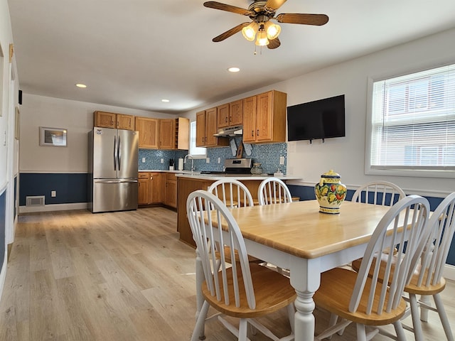 kitchen with brown cabinets, light wood-style flooring, appliances with stainless steel finishes, and tasteful backsplash