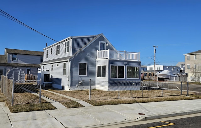 view of front of house with a balcony and a fenced front yard