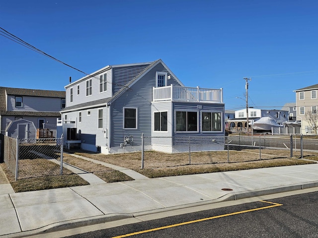 view of front of home featuring a balcony and a fenced front yard