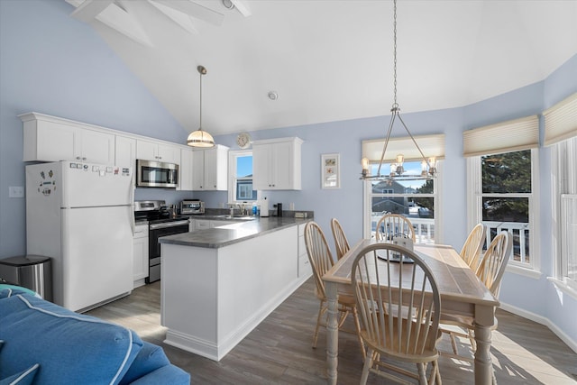 kitchen with decorative light fixtures, white cabinets, kitchen peninsula, and appliances with stainless steel finishes