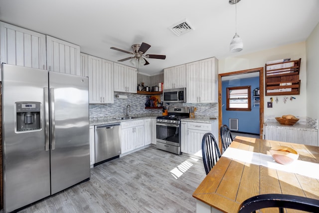 kitchen featuring backsplash, hanging light fixtures, ceiling fan, white cabinetry, and stainless steel appliances