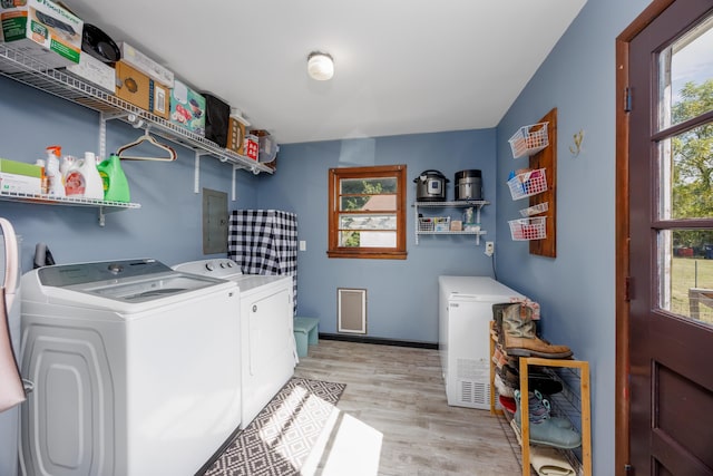 laundry area featuring electric panel, light wood-type flooring, and independent washer and dryer