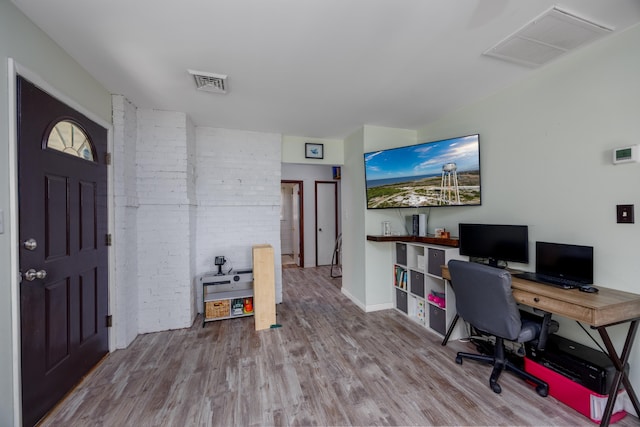 office area with brick wall and hardwood / wood-style flooring