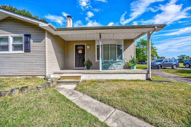 property entrance featuring a lawn and covered porch