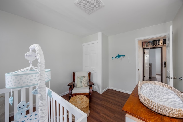 bedroom featuring a crib and dark wood-type flooring