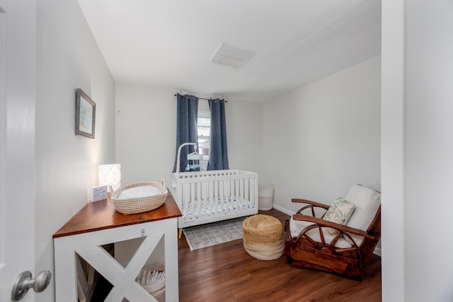 bedroom featuring a nursery area and dark hardwood / wood-style floors