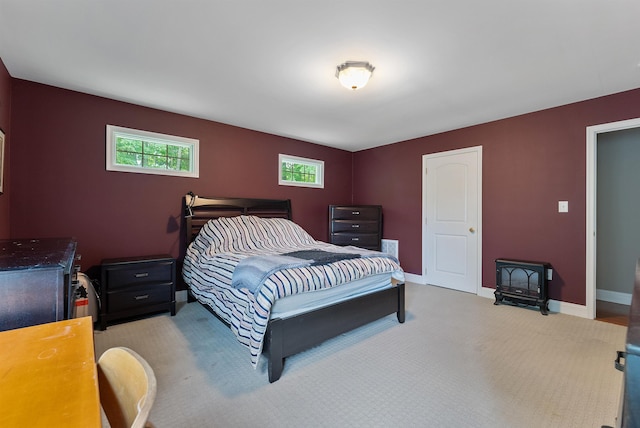 bedroom with baseboards, a wood stove, and light carpet