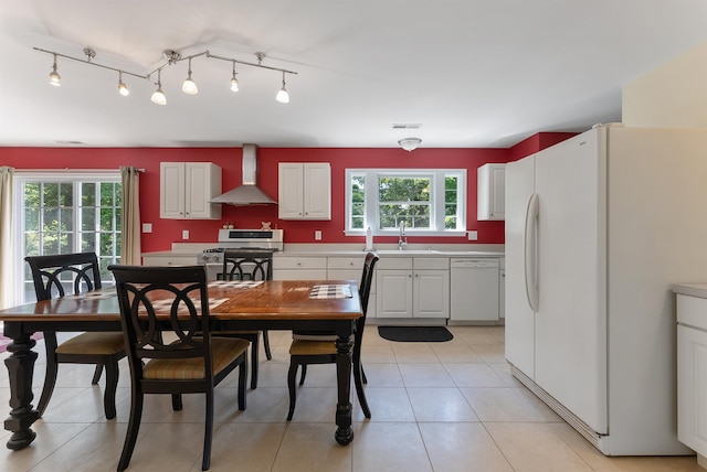 kitchen featuring wall chimney exhaust hood, a sink, white appliances, and plenty of natural light