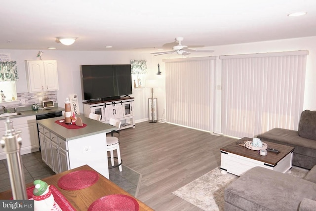 living room featuring ceiling fan, sink, and light wood-type flooring