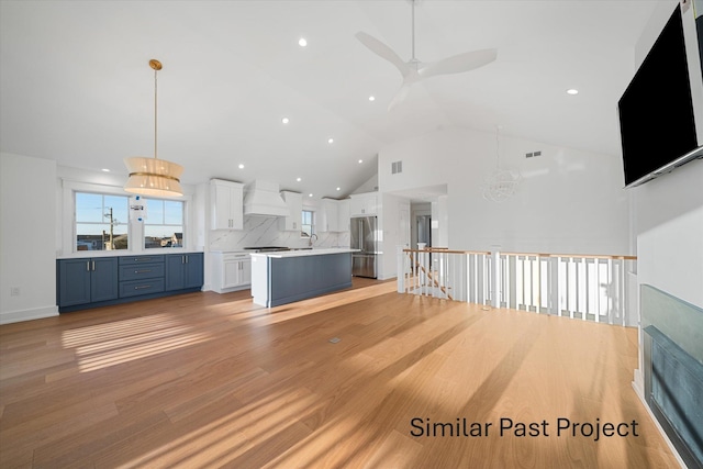 kitchen featuring white cabinetry, hanging light fixtures, a kitchen island, blue cabinets, and custom range hood