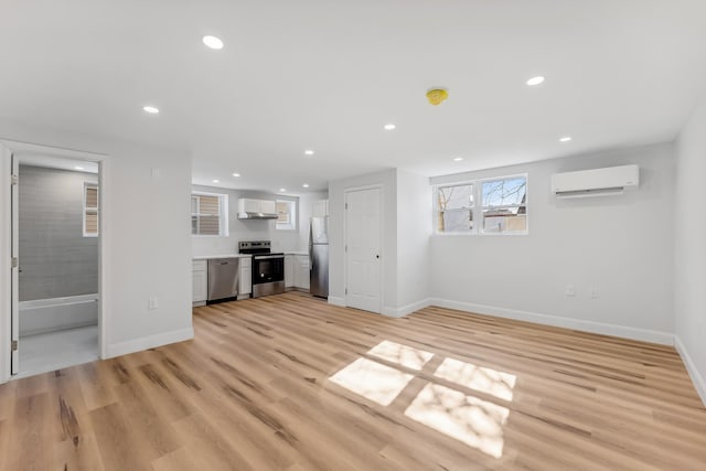 unfurnished living room with recessed lighting, light wood-style flooring, and a wall mounted AC