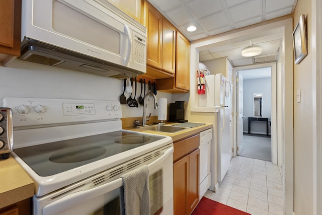 kitchen with white appliances, a drop ceiling, light tile patterned flooring, and sink