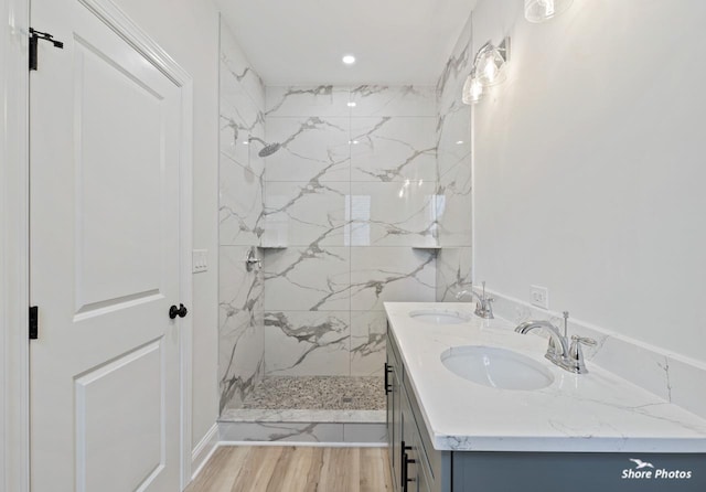 full bathroom featuring a marble finish shower, wood finished floors, double vanity, and recessed lighting