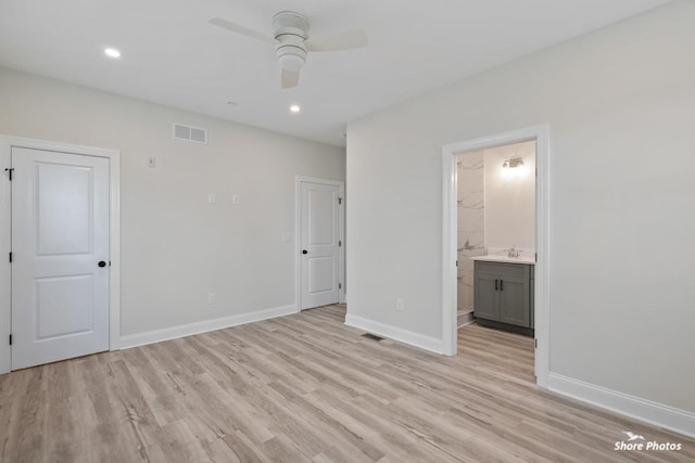 unfurnished bedroom featuring light wood-style floors, baseboards, ensuite bathroom, recessed lighting, and a sink