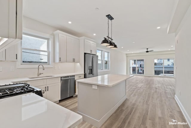 kitchen featuring appliances with stainless steel finishes, a sink, a center island, pendant lighting, and recessed lighting