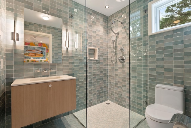 bathroom with walk in shower, tile patterned floors, toilet, tile walls, and vanity