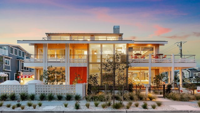 back house at dusk featuring a balcony