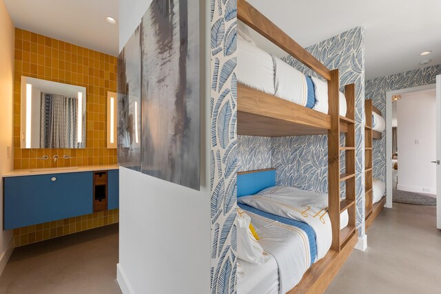 bedroom featuring sink, concrete floors, and tile walls