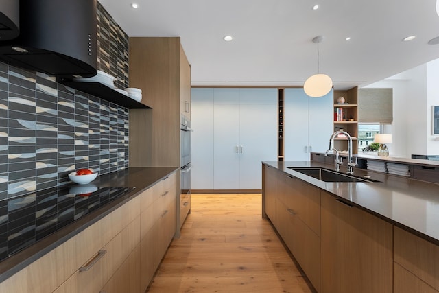 kitchen featuring pendant lighting, ventilation hood, sink, backsplash, and light hardwood / wood-style flooring