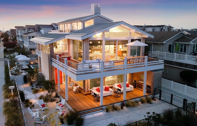 back house at dusk with a wooden deck and an outdoor hangout area