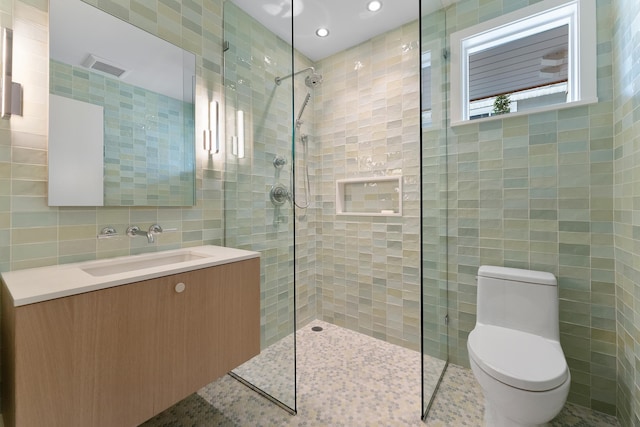 bathroom featuring vanity, toilet, tile walls, and a tile shower