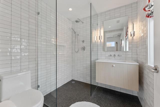 bathroom with tile walls, vanity, a shower with shower door, and toilet