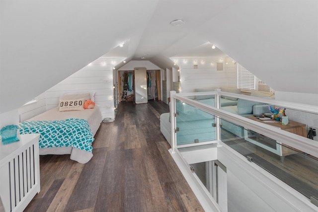 bedroom with wooden walls, vaulted ceiling, and wood finished floors