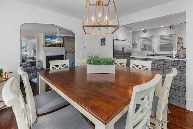 dining space featuring arched walkways, wood finished floors, and a fireplace