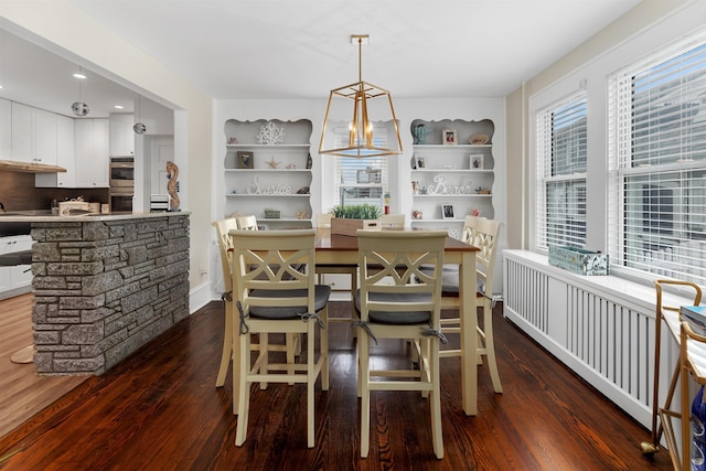 dining space with built in shelves, plenty of natural light, and dark wood finished floors