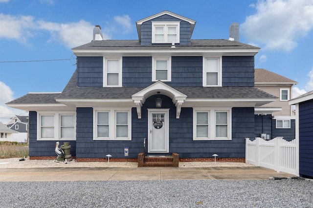 view of front of property featuring roof with shingles, a chimney, and fence