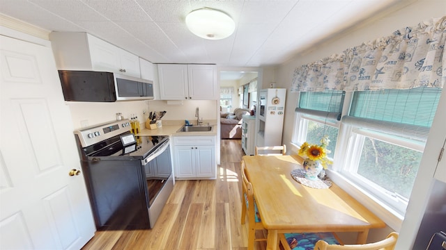 kitchen with stainless steel range with electric cooktop, white cabinets, sink, light wood-type flooring, and white fridge