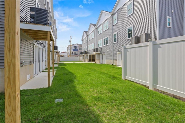 view of yard with a residential view, central air condition unit, and fence