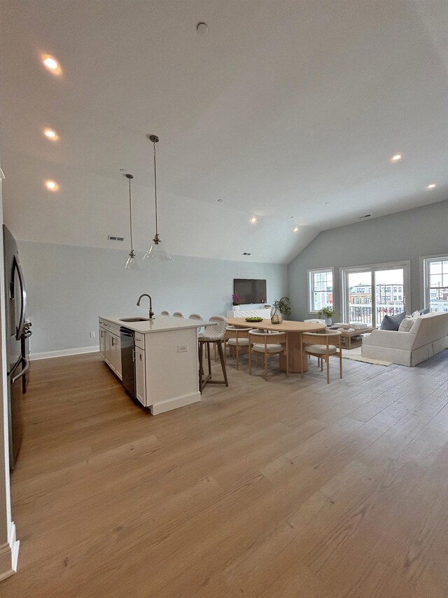 kitchen featuring lofted ceiling, a sink, open floor plan, light wood-type flooring, and stainless steel fridge