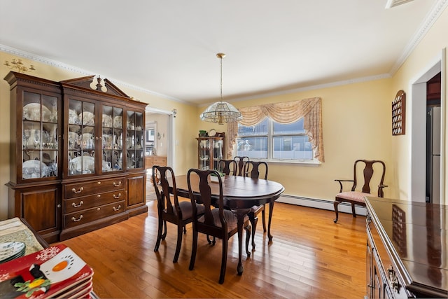 dining room featuring crown molding, a notable chandelier, hardwood / wood-style flooring, and baseboard heating