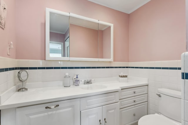 bathroom with vanity, toilet, and tile walls