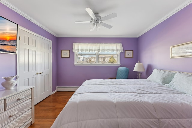 bedroom featuring ornamental molding, hardwood / wood-style floors, a closet, and a baseboard heating unit