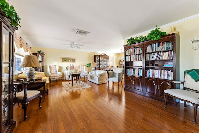 living room with wood-type flooring, ornamental molding, and ceiling fan