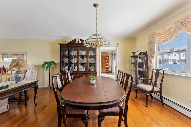 dining space featuring an inviting chandelier, ornamental molding, light hardwood / wood-style flooring, and a baseboard heating unit