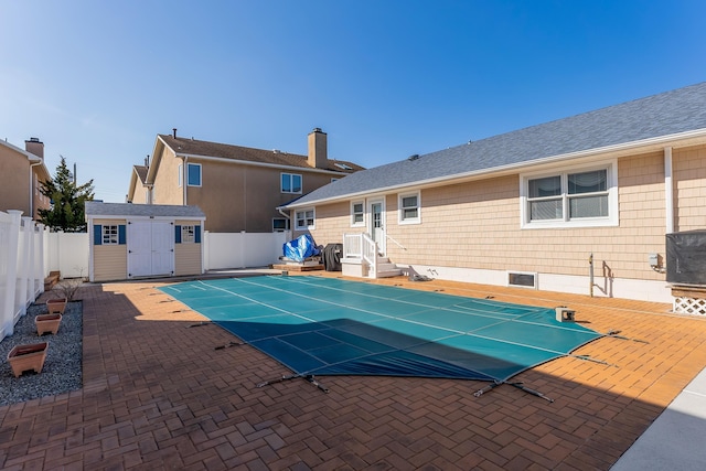 view of swimming pool featuring a storage unit and a patio