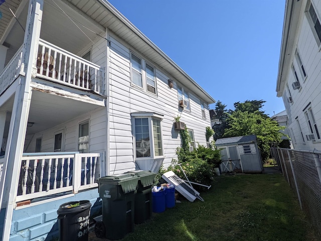 back of house featuring a lawn, a balcony, and a storage shed