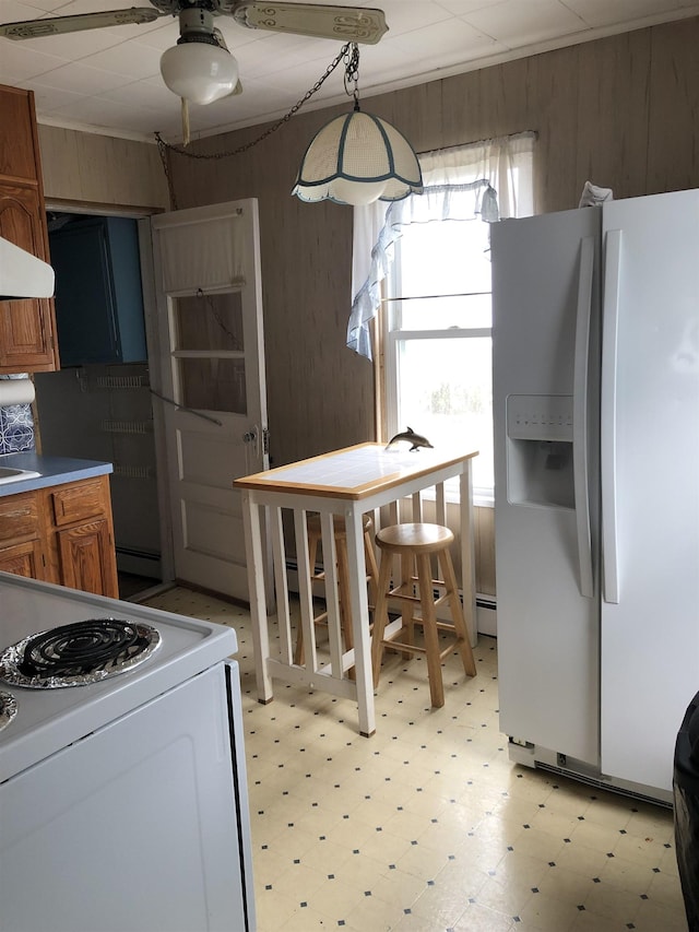 kitchen with sink, hanging light fixtures, extractor fan, white appliances, and wooden walls