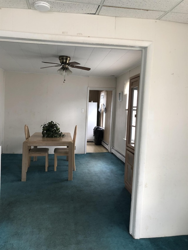 unfurnished dining area featuring baseboard heating, ceiling fan, and carpet floors