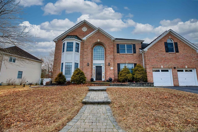 view of front facade with aphalt driveway, an attached garage, and brick siding