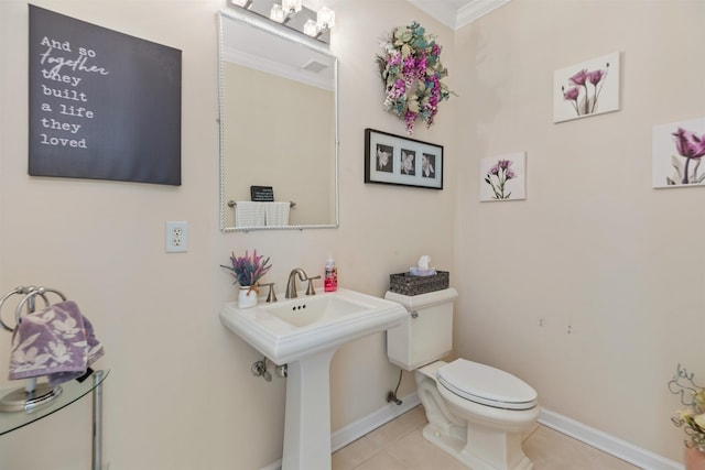 half bathroom with baseboards, a sink, toilet, and tile patterned floors