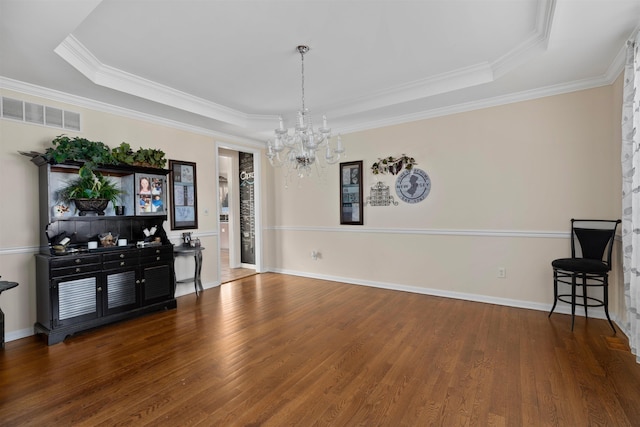 interior space featuring a notable chandelier, visible vents, a raised ceiling, and wood finished floors