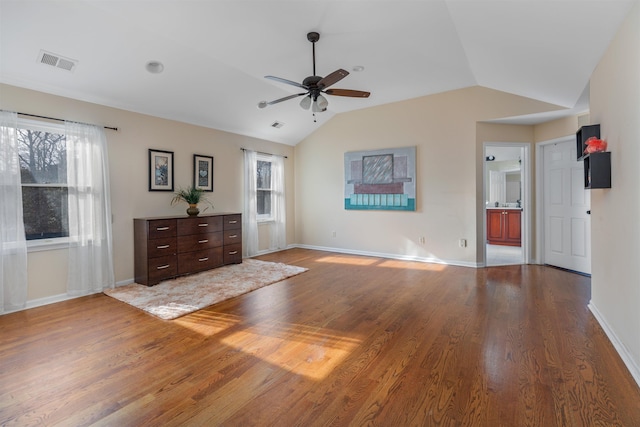 interior space with vaulted ceiling, wood finished floors, visible vents, and baseboards